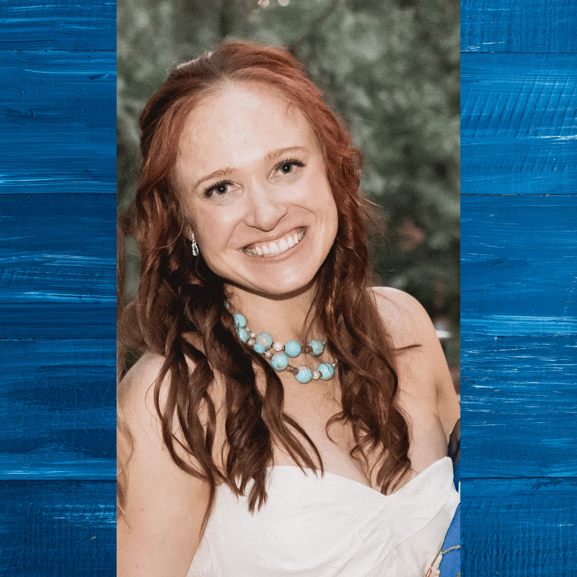 A woman wearing a white dress and a blue necklace is smiling