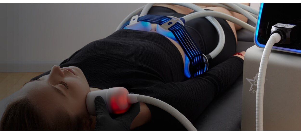 A woman is laying on a bed with a machine on her stomach.