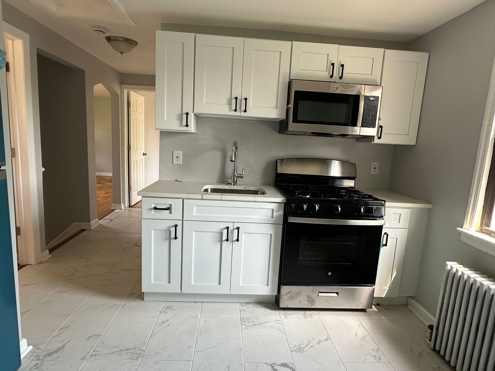 Small kitchen with white cabinets, stainless steel appliances, and light gray walls.