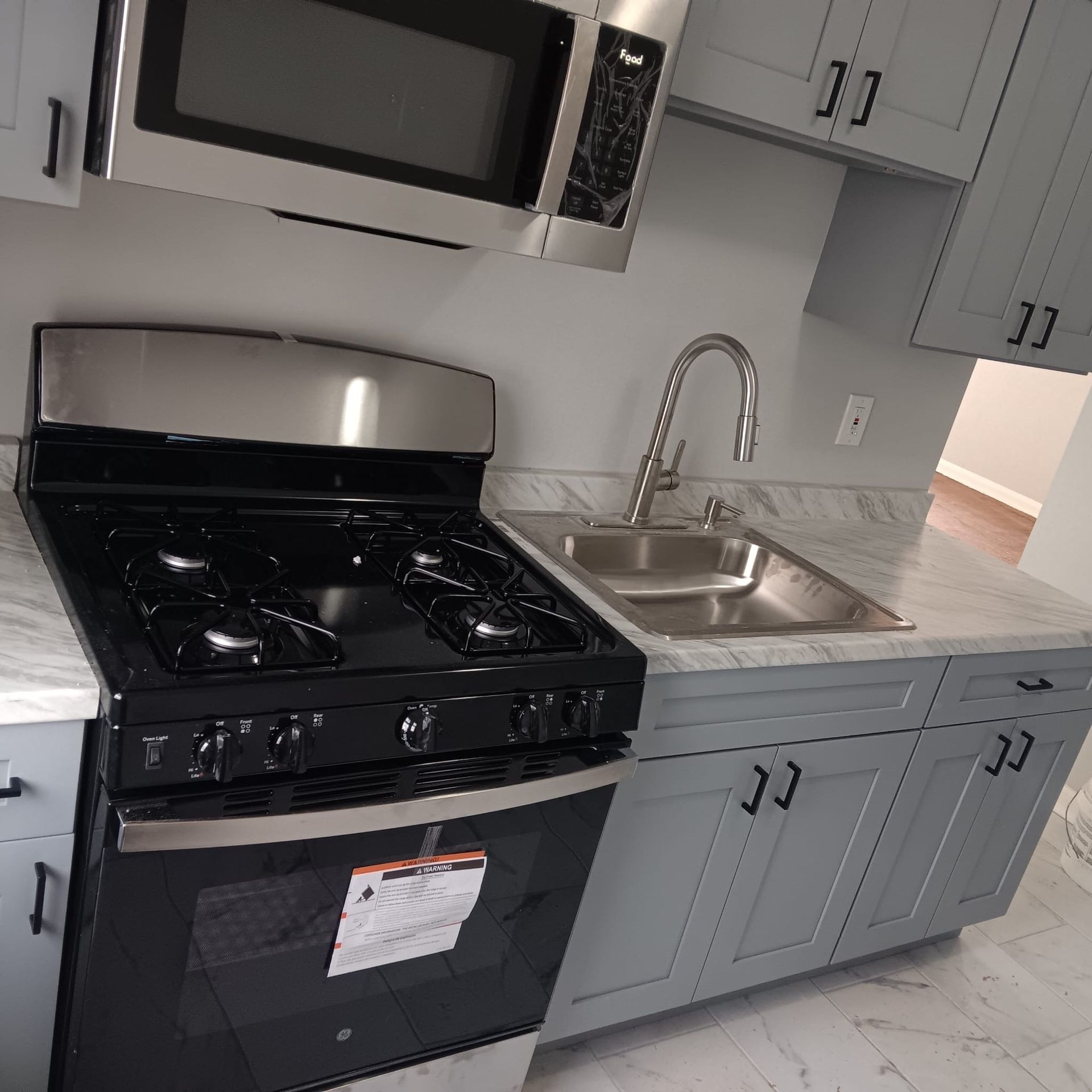 Kitchen with gray cabinets, stainless steel appliances, and marble countertops.