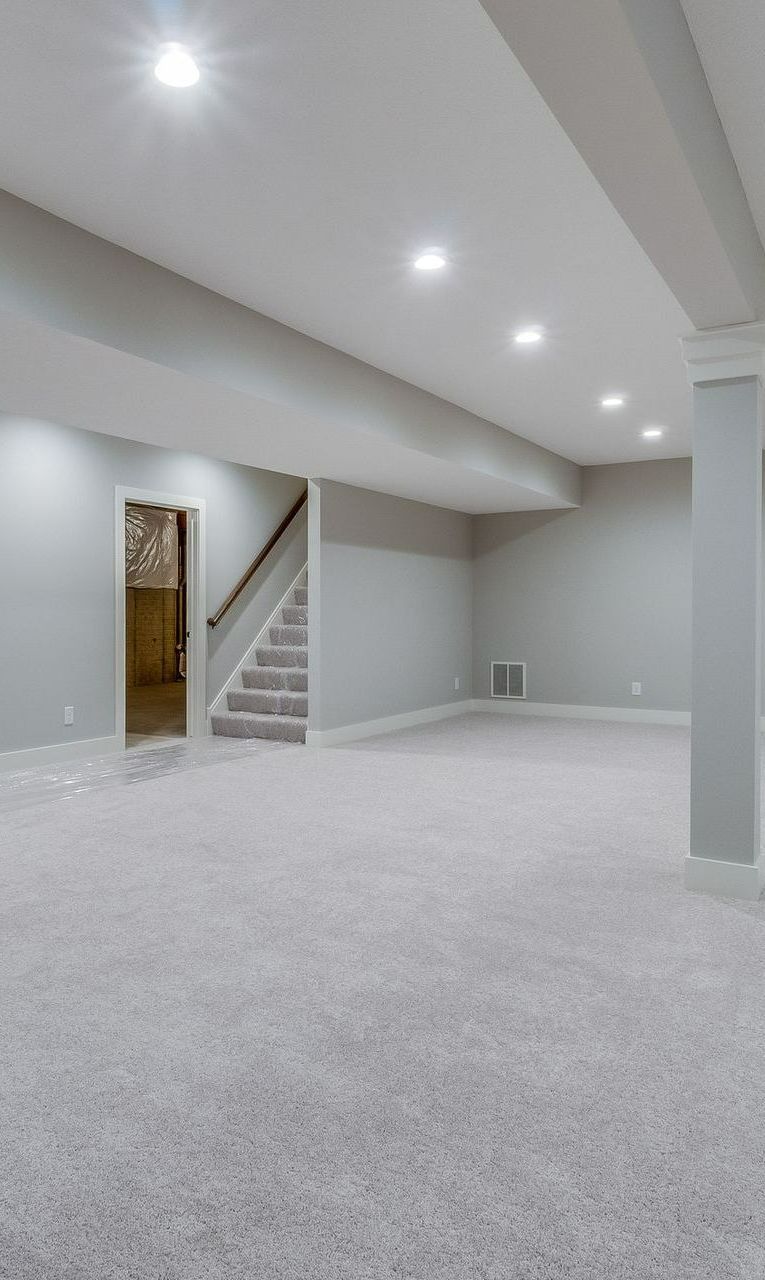 An empty basement with carpeted floors and stairs. An empty basement with carpeted floors and stairs.