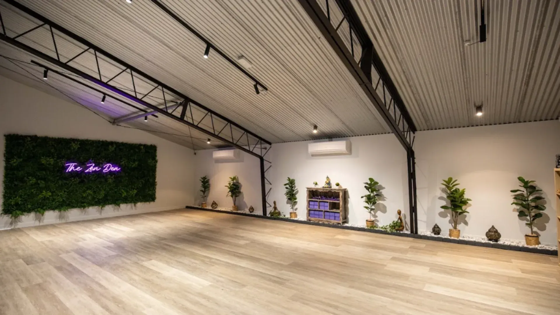 A large empty room with a wooden floor and a green wall.