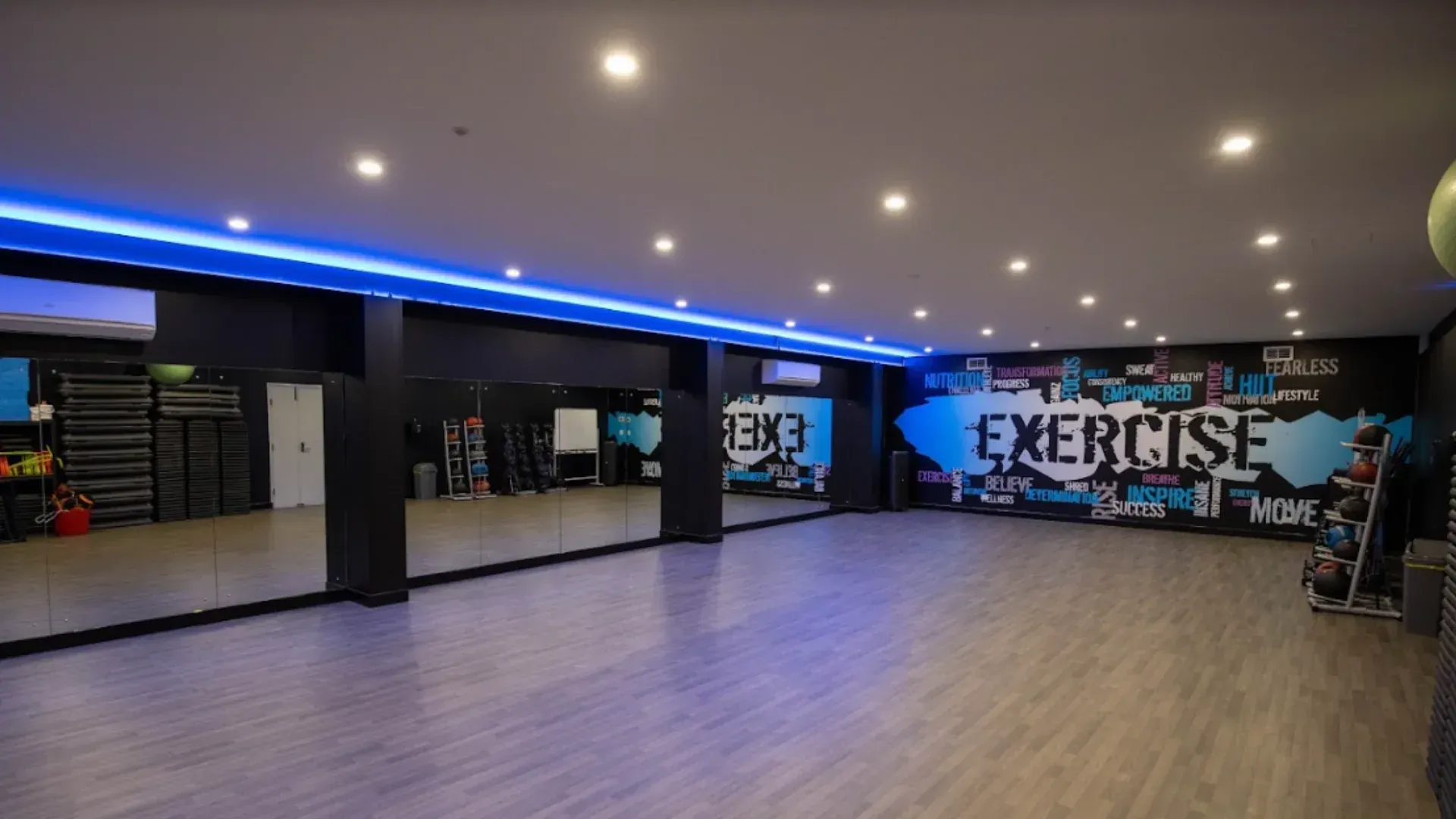 A large empty gym with a mural on the wall that says exercise.