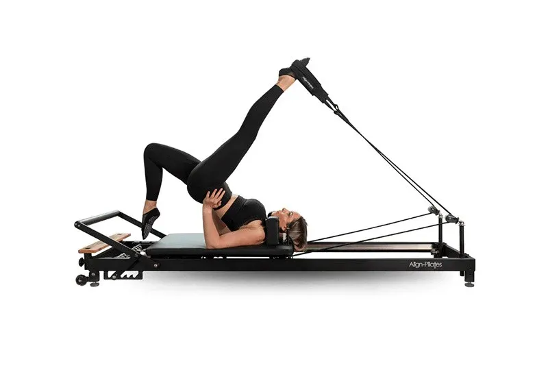 A woman is doing a handstand on a pilates machine.