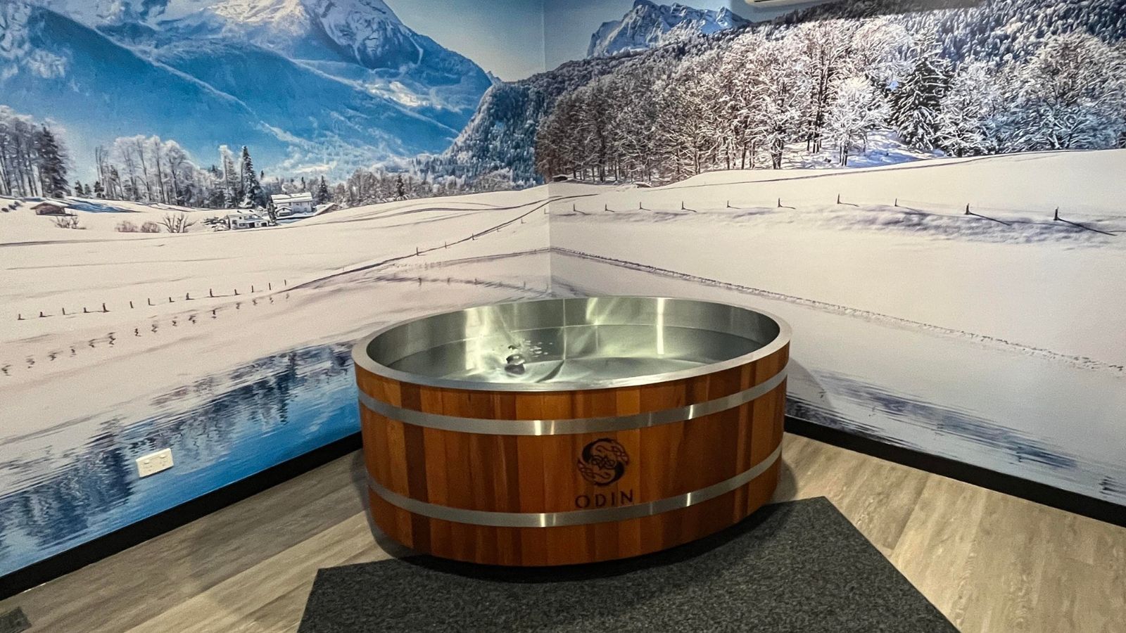 A wooden tub is sitting in a room with a picture of a snowy mountain on the wall.