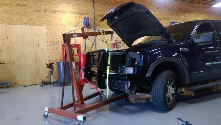 a truck is being worked on in a garage with the hood open