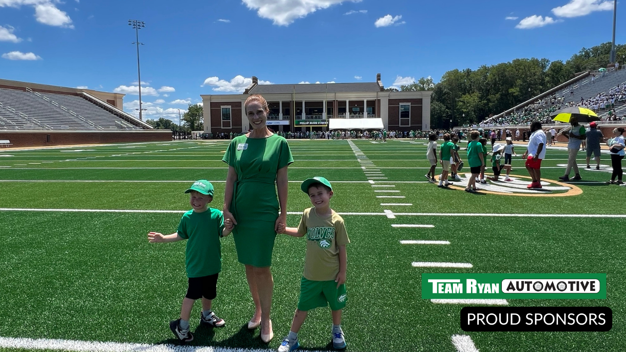 Woman and two children in green on a football field. Team Ryan Automotive proudly sponsors the event.