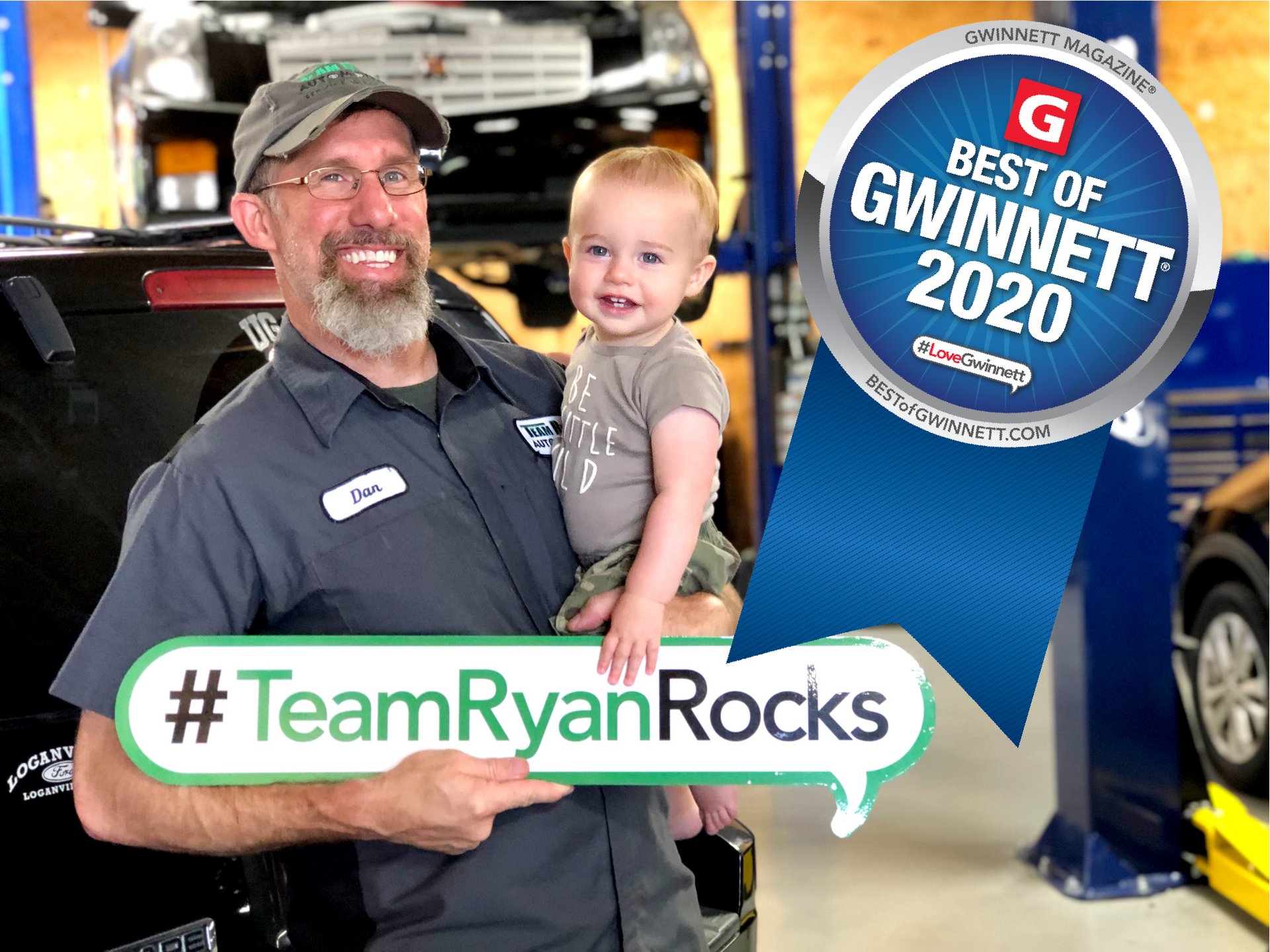 Team Ryan Automotive owner is holding a baby in his arms in front of a car.