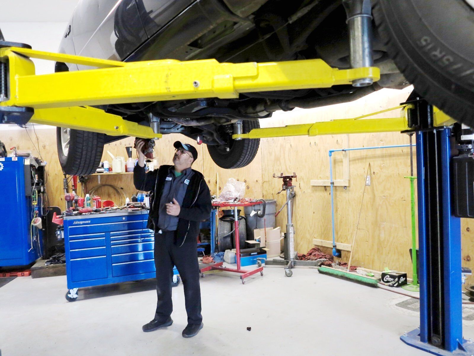 a man is standing under a car on a lift in a garage