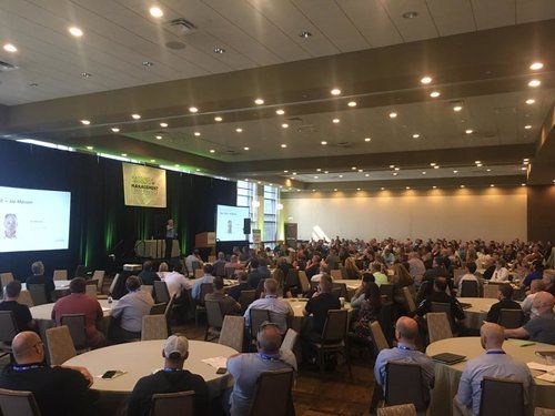 a large group of people are sitting at tables in a conference room .
