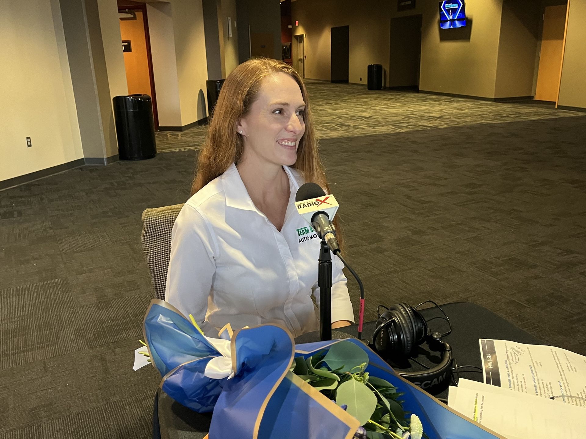 a woman in a white shirt is sitting in front of a microphone