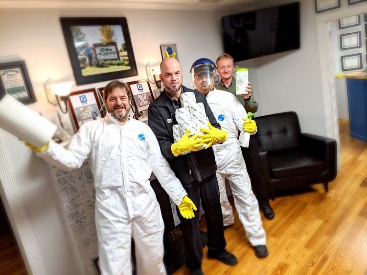 a group of men wearing white coveralls and yellow gloves are posing for a picture .