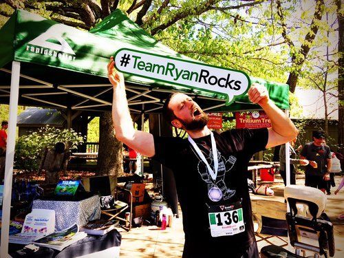 a man holding up a sign that says team ryan rocks