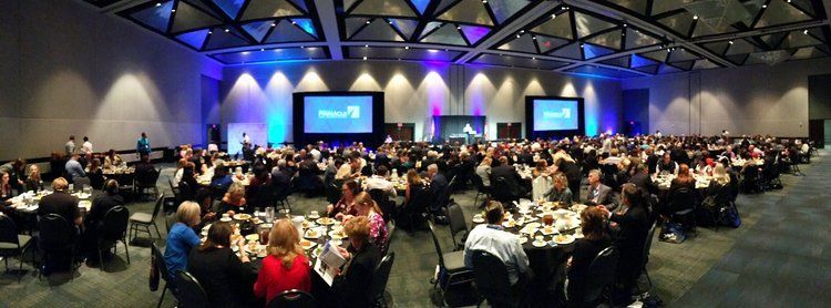 a large group of people are sitting at tables in a large room