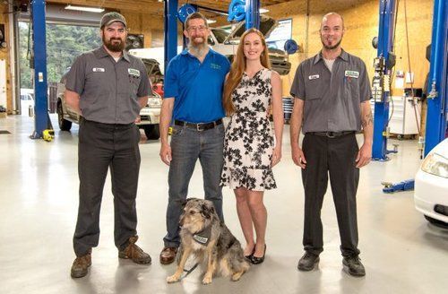 a group of people standing next to each other in a garage with a dog .