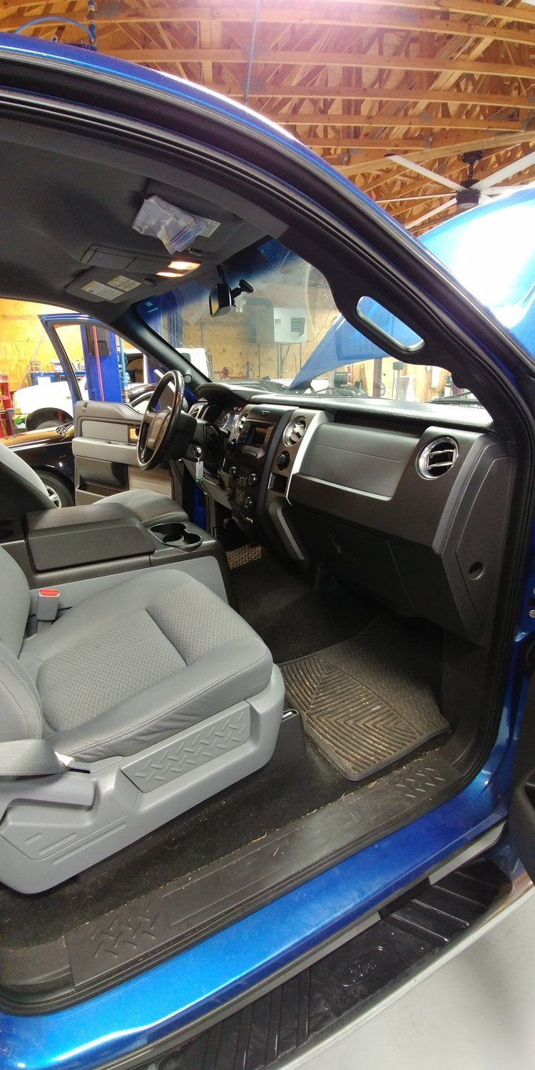 the interior of a blue truck with the door open in a garage - evaporator and heater core replacement