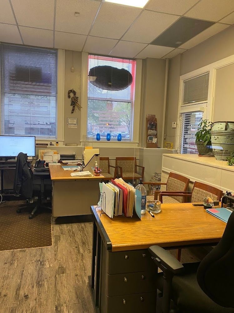 A room with a lot of desks and chairs and a window.