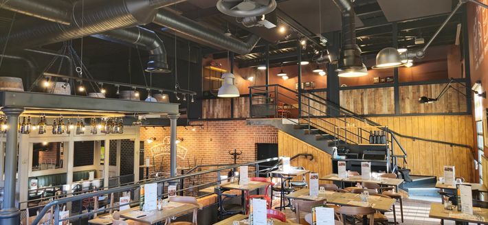 Un restaurant avec beaucoup de tables et de chaises et un escalier.