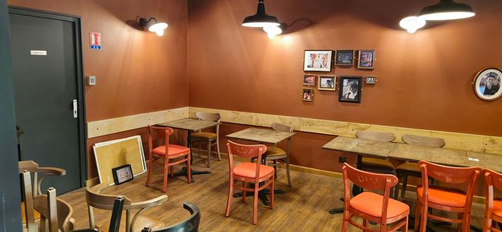 Une salle à manger avec tables et chaises et tableaux au mur.