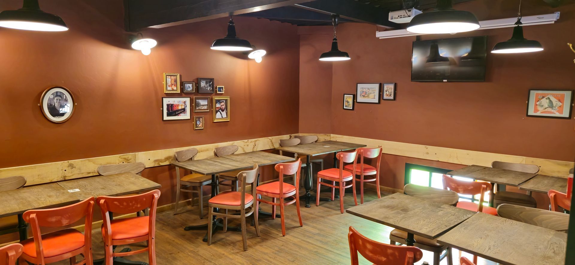 Un restaurant avec tables et chaises et une télévision au mur.