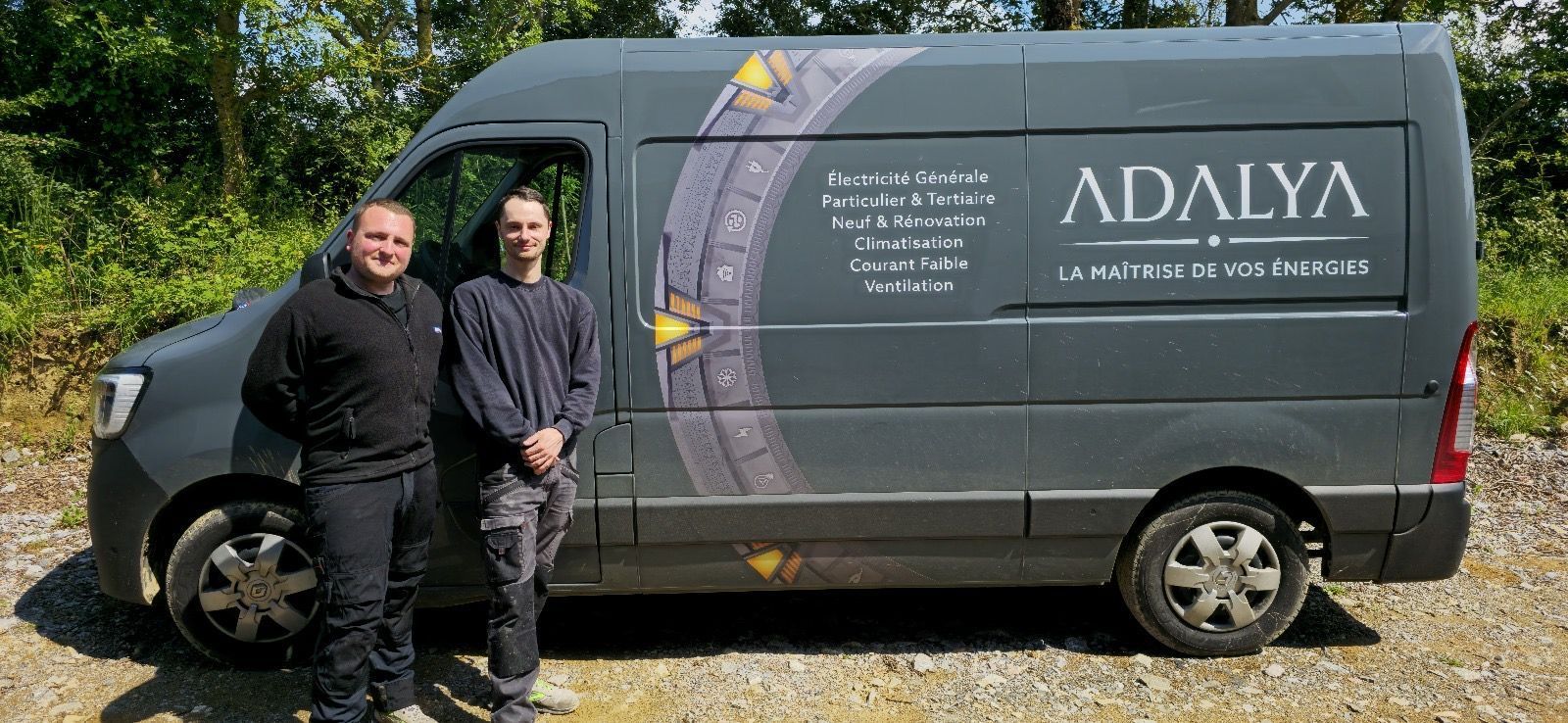 Deux hommes se tiennent à côté d'une camionnette indiquant adalya.