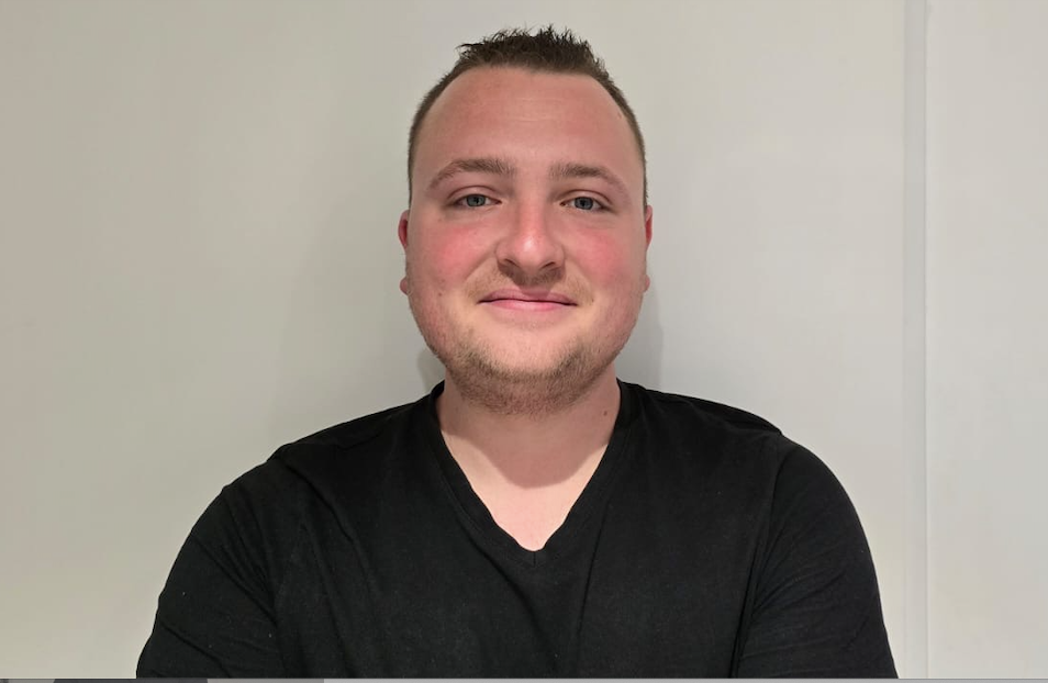 Un homme en chemise noire sourit à la caméra