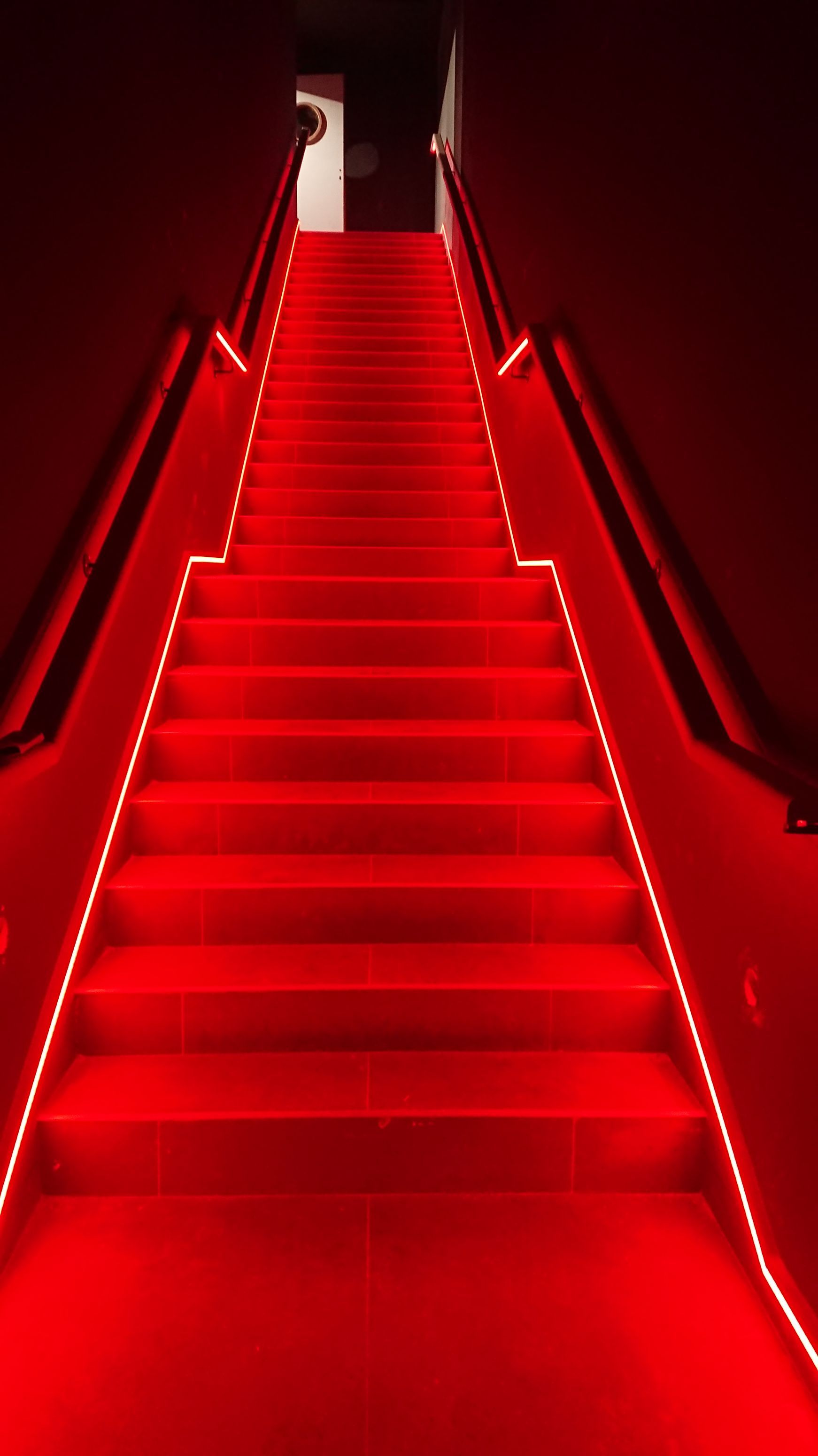 Un escalier rouge avec des lumières rouges sur les marches.