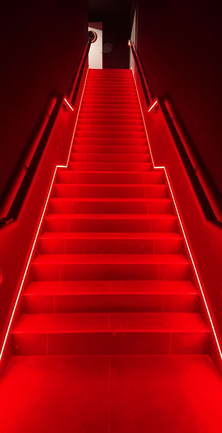 Les escaliers sont éclairés par des lumières rouges et un tapis rouge.