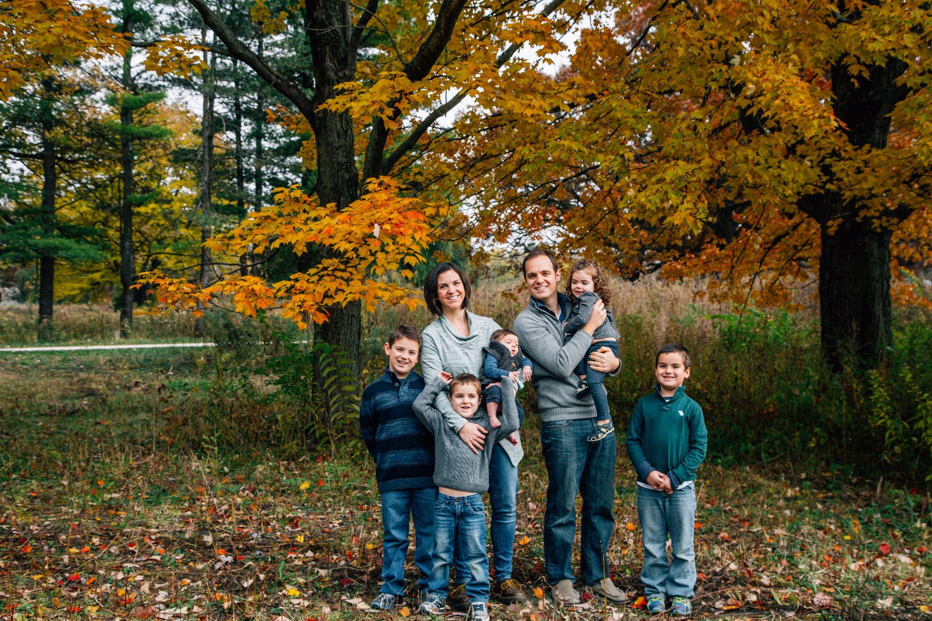 A family is posing for a picture in the woods.