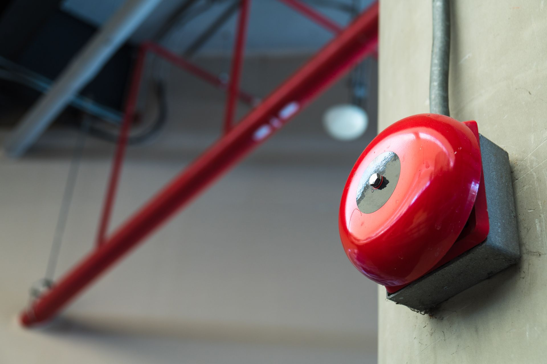 Red fire alarm on a beige wall with a red pipe in the background. Red fire alarm on a beige wall with a red pipe in the background.