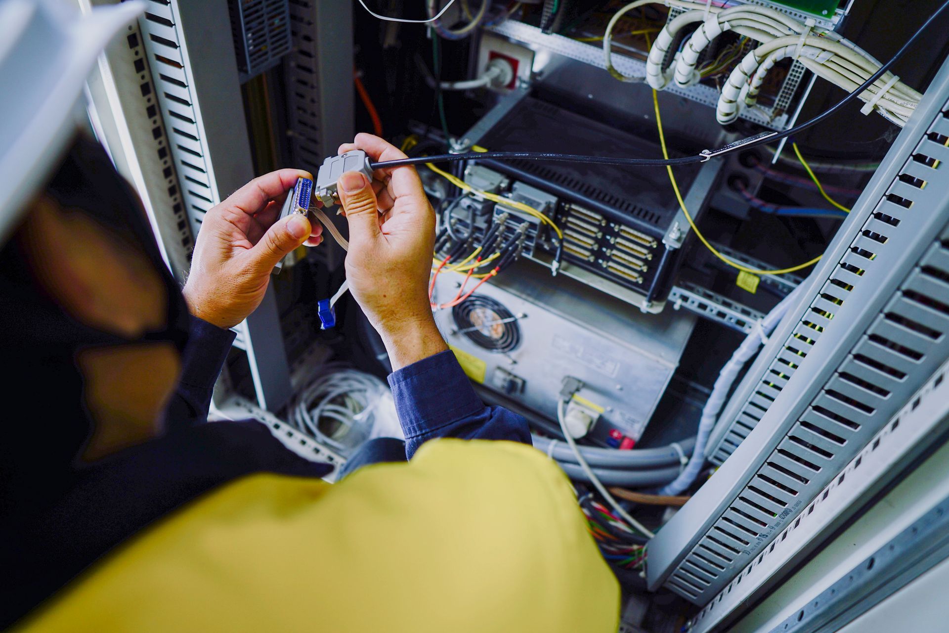 Technician working on server equipment inside a rack, focused on cables and connections.