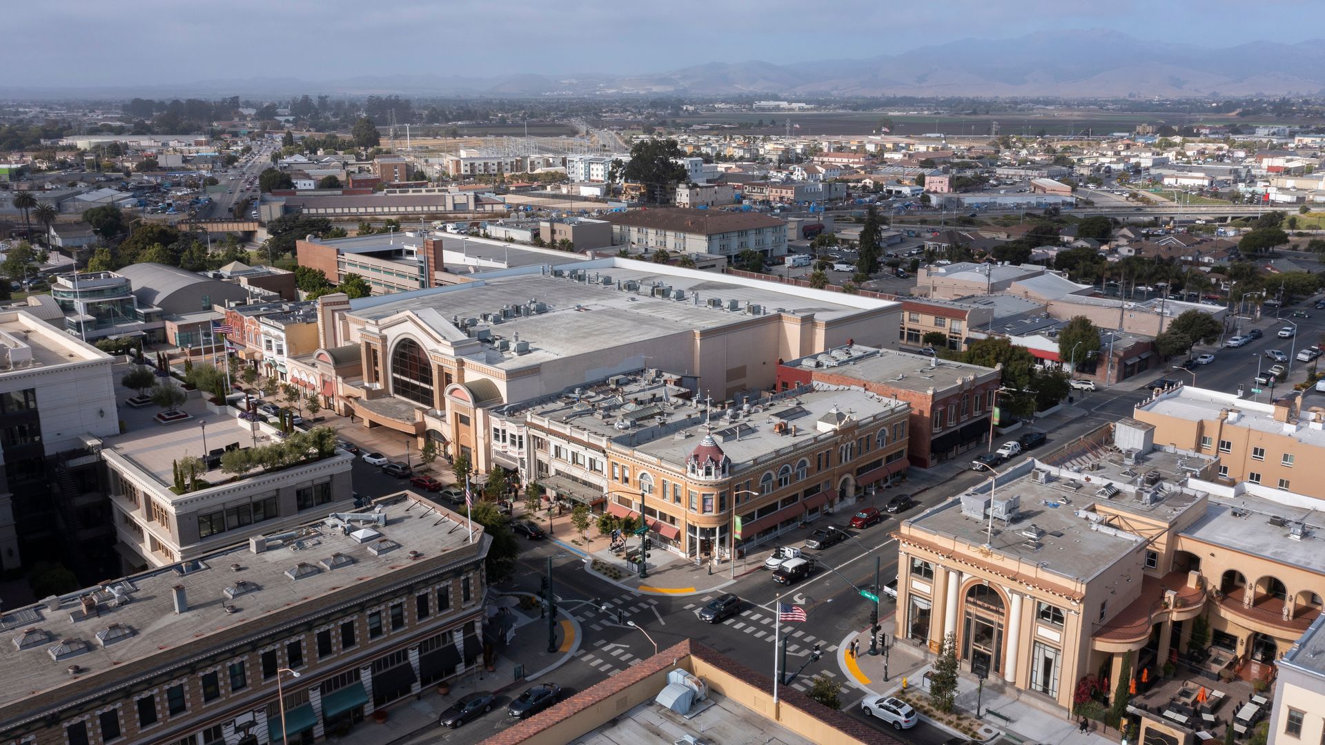 Aerial view of a city street with a large building and multiple smaller buildings. Aerial view of a city street with a large building and multiple smaller buildings.