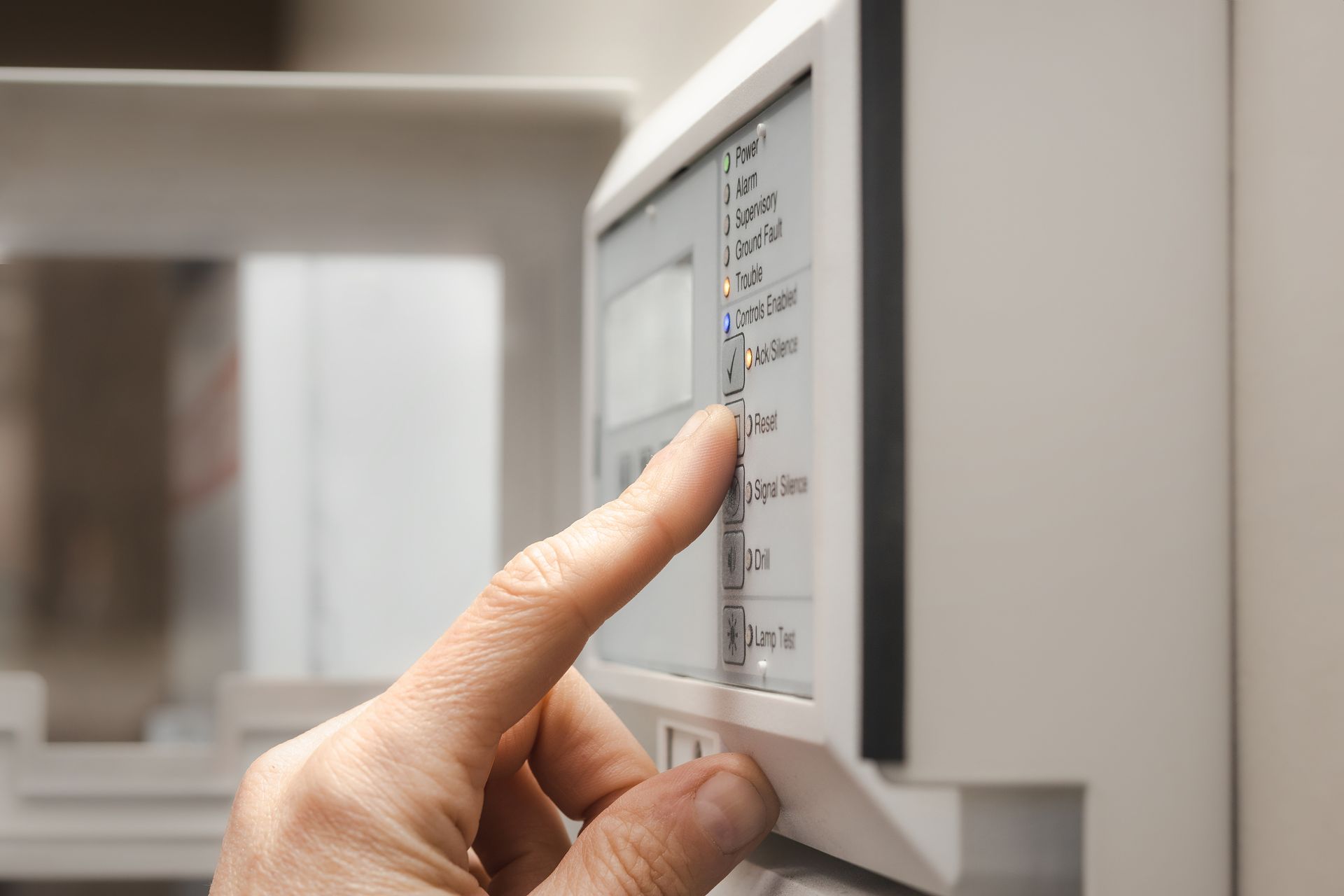 A hand presses a button on a white appliance control panel, likely a refrigerator.
