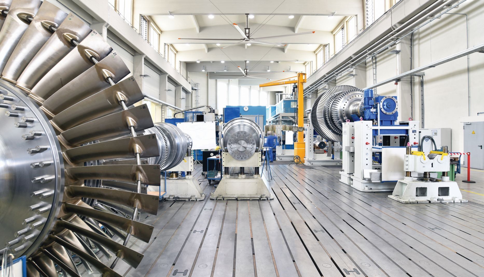 A factory with a lot of machinery and a large turbine in the middle of the room.