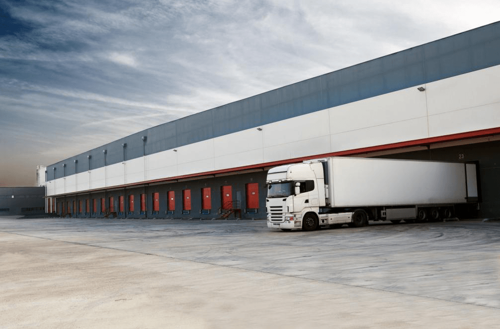 A white truck is parked in front of a warehouse.