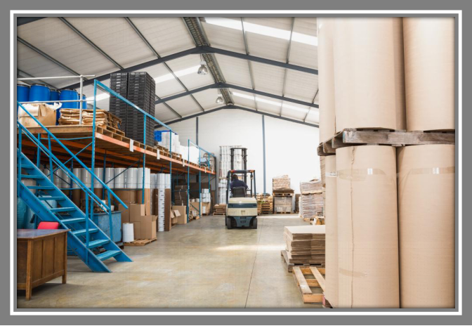 A warehouse with a forklift and stacks of cardboard rolls