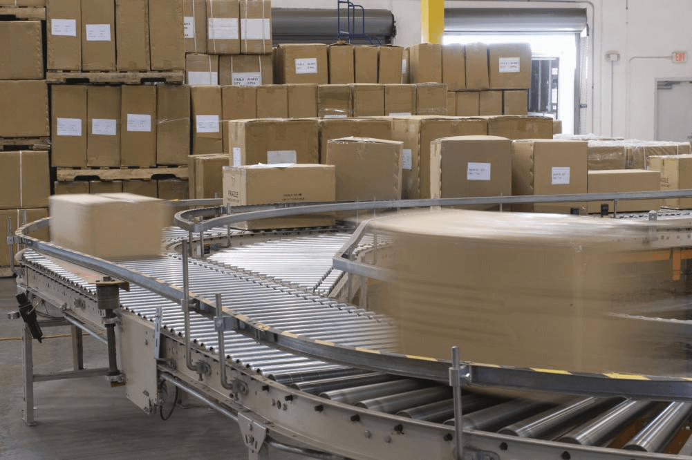 Boxes are moving on a conveyor belt in a warehouse.
