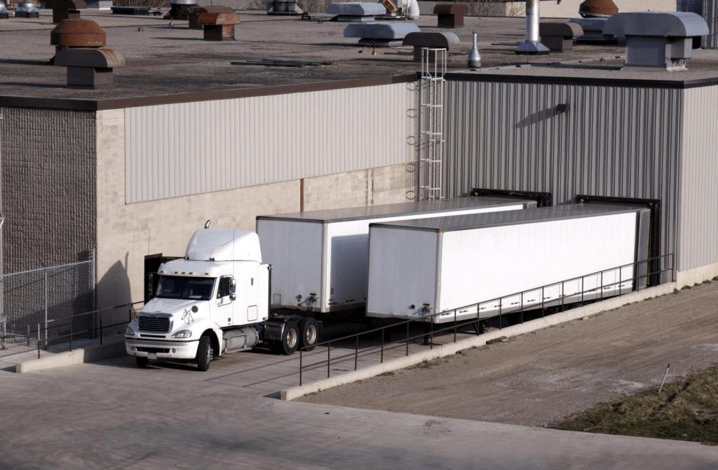 A white semi truck is parked in front of a building