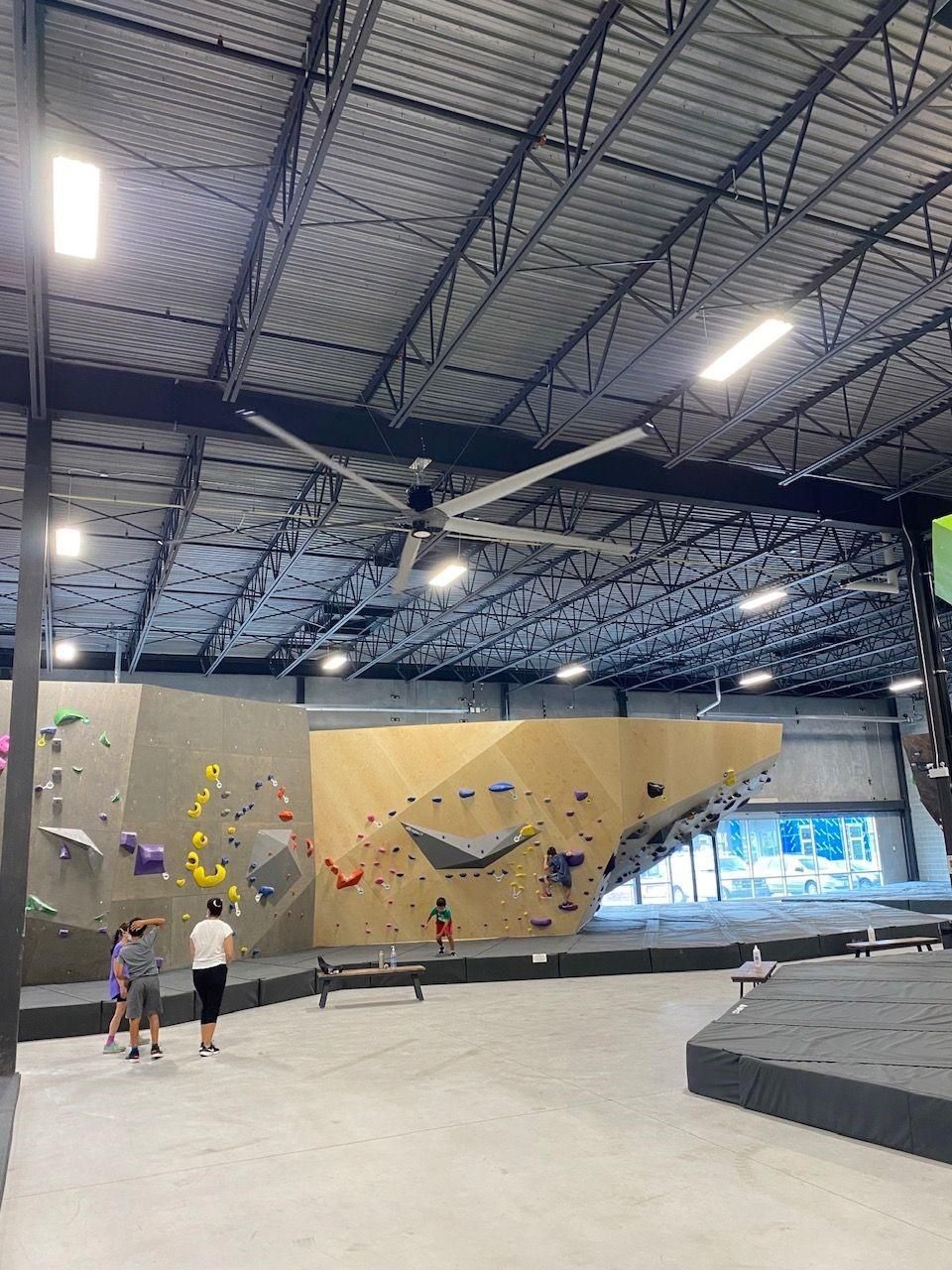 A group of people are standing in front of a climbing wall in a gym.