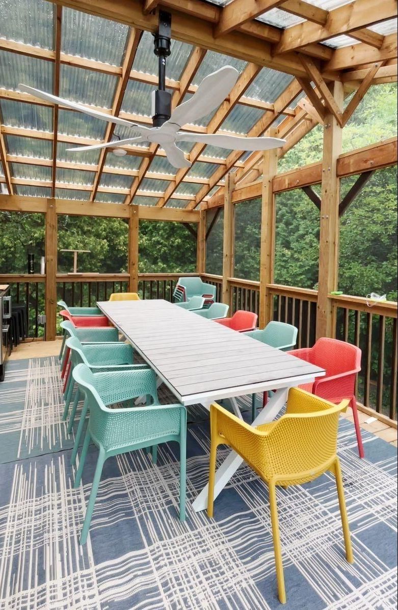 A screened in porch with a table and chairs and a ceiling fan.