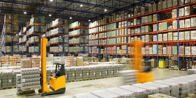 A man is driving a forklift in a large warehouse.