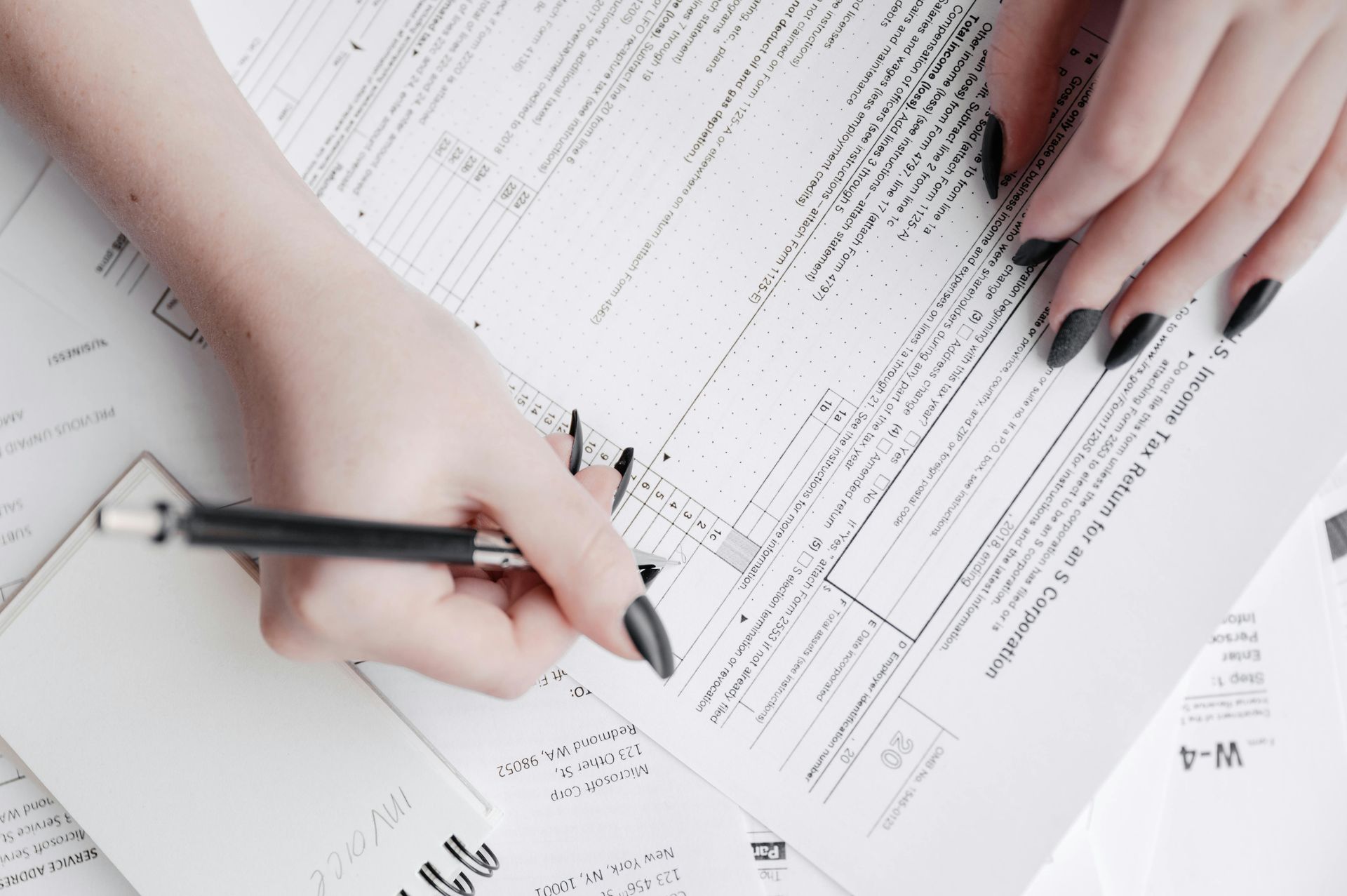 A woman is writing on a piece of paper with a pen.