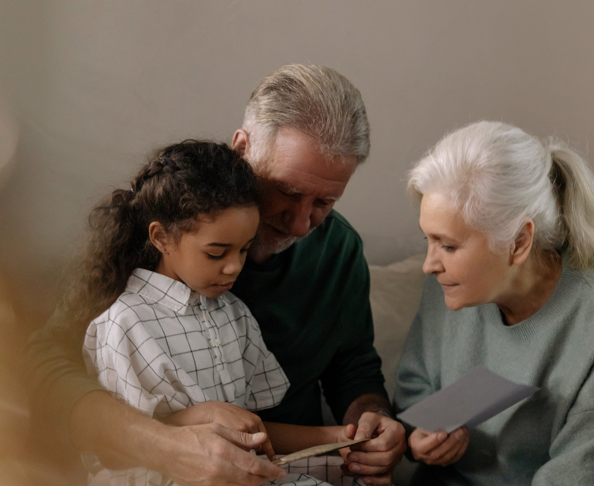 A young girl is sitting at a table with an older woman standing behind her.
