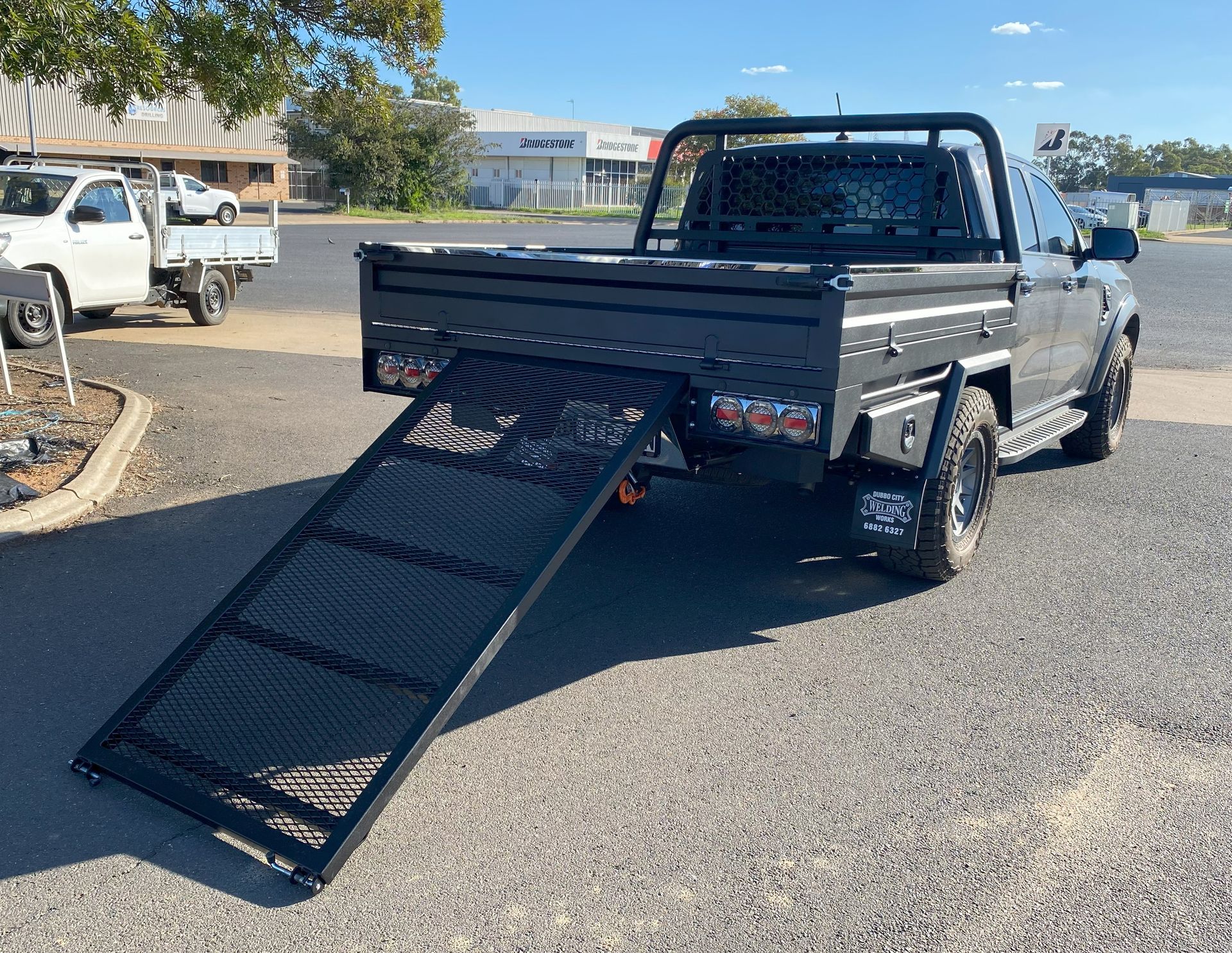 A truck with a ramp attached to the back of it is parked on the side of the road.