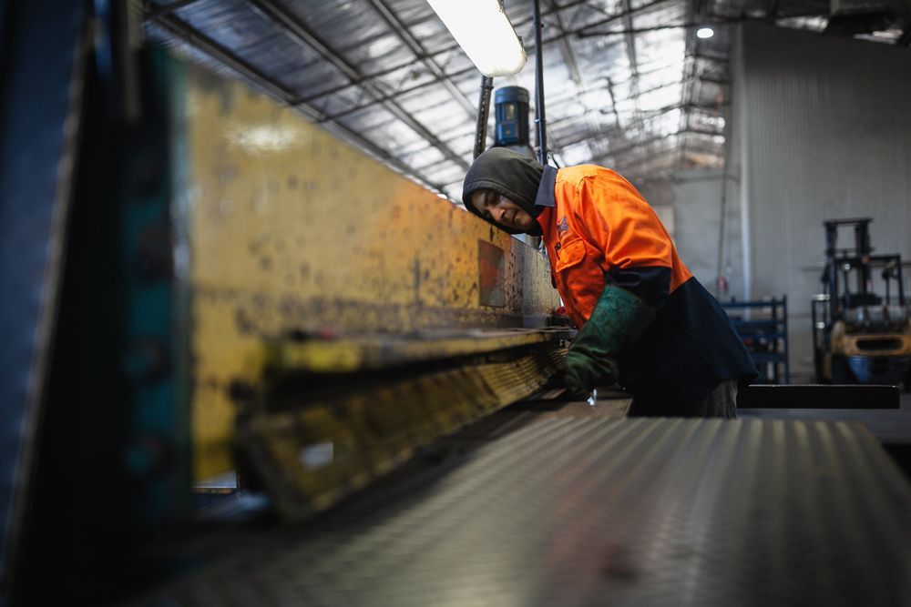 Man Wearing Uniform Checking Steel Tray — Welding Works in Forbes, NSW