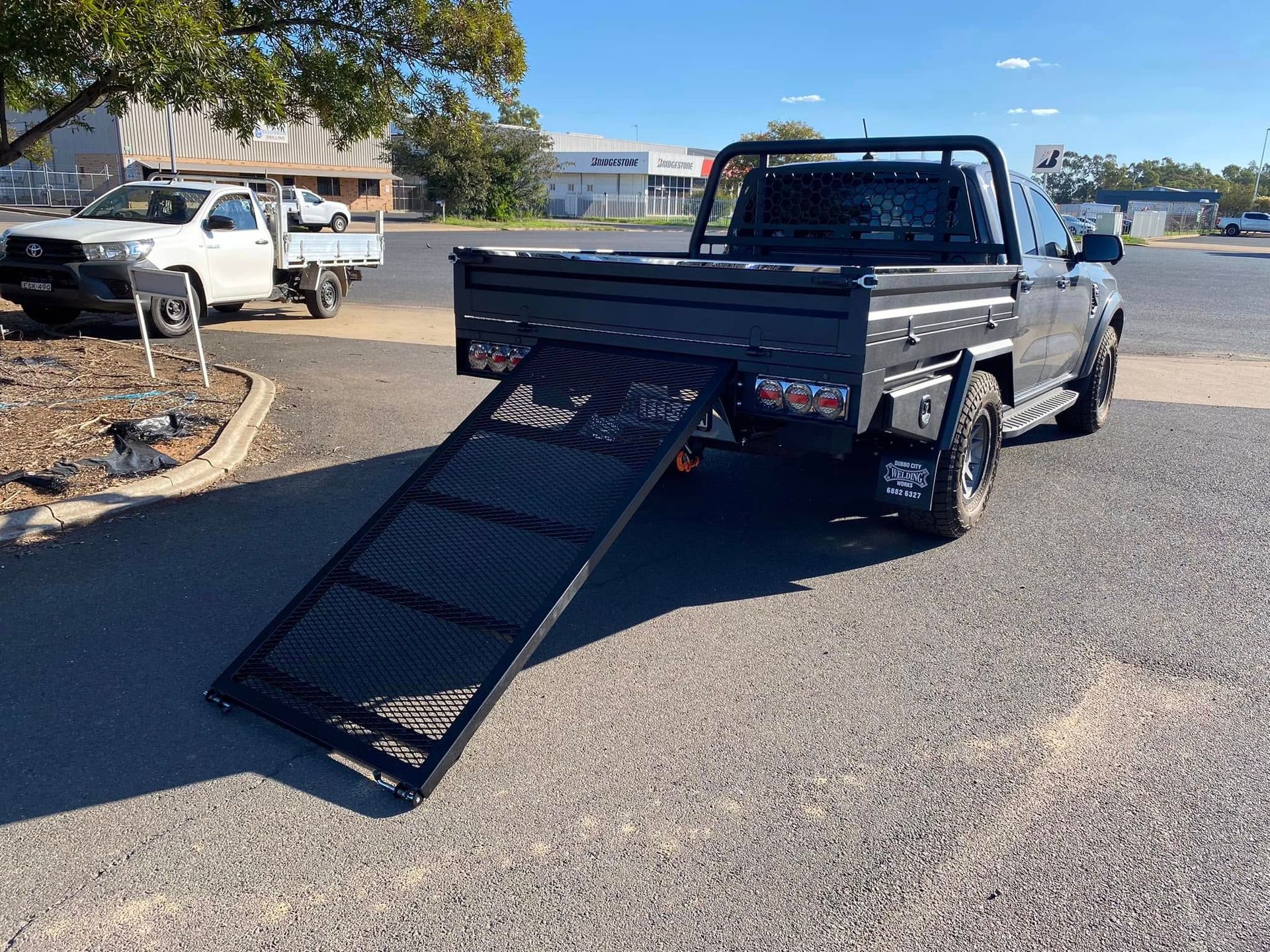 Black pickup truck with a ramp in a parking lot on a sunny day