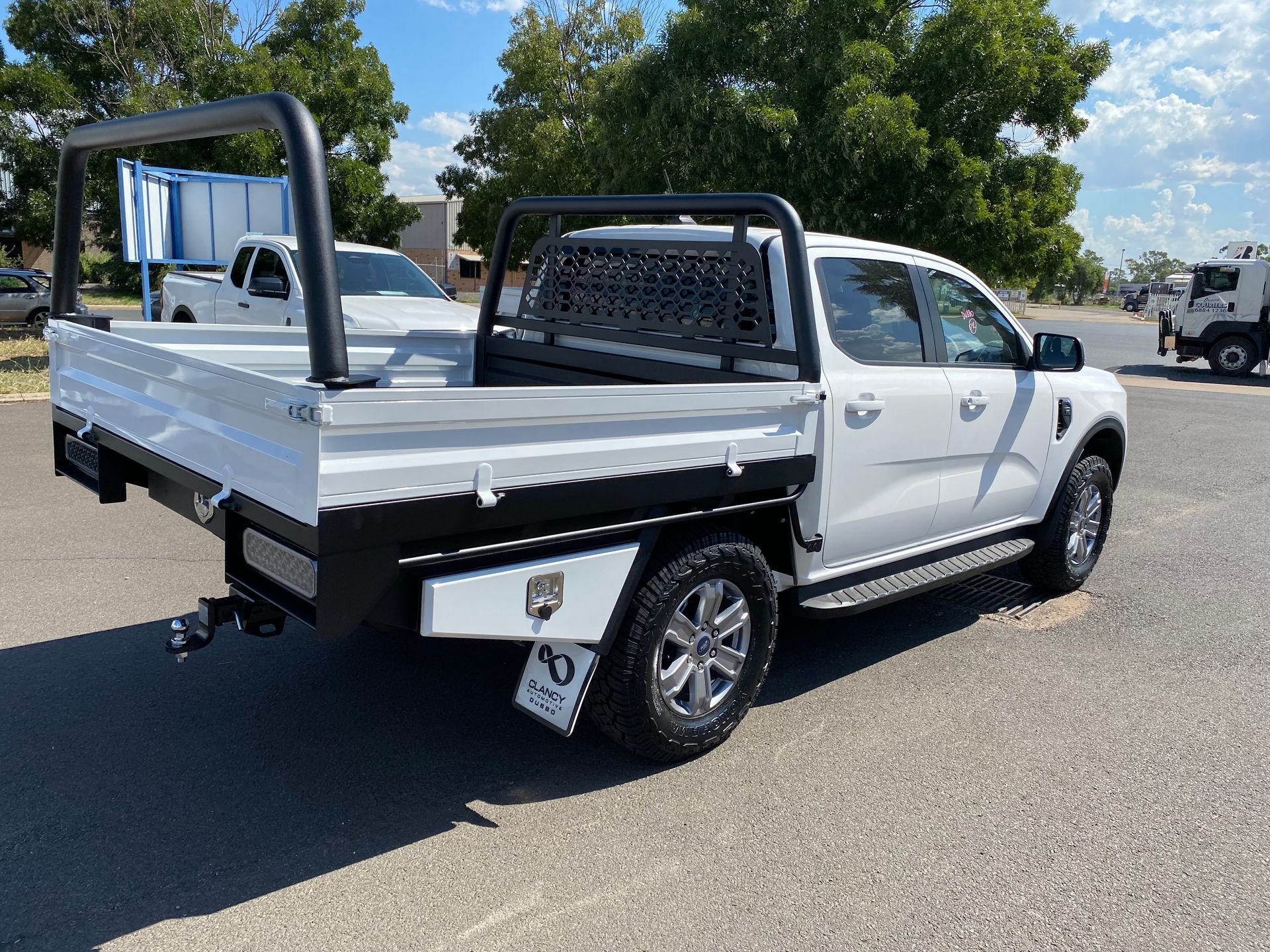 A white truck with a tray bed is parked on the side of the road.