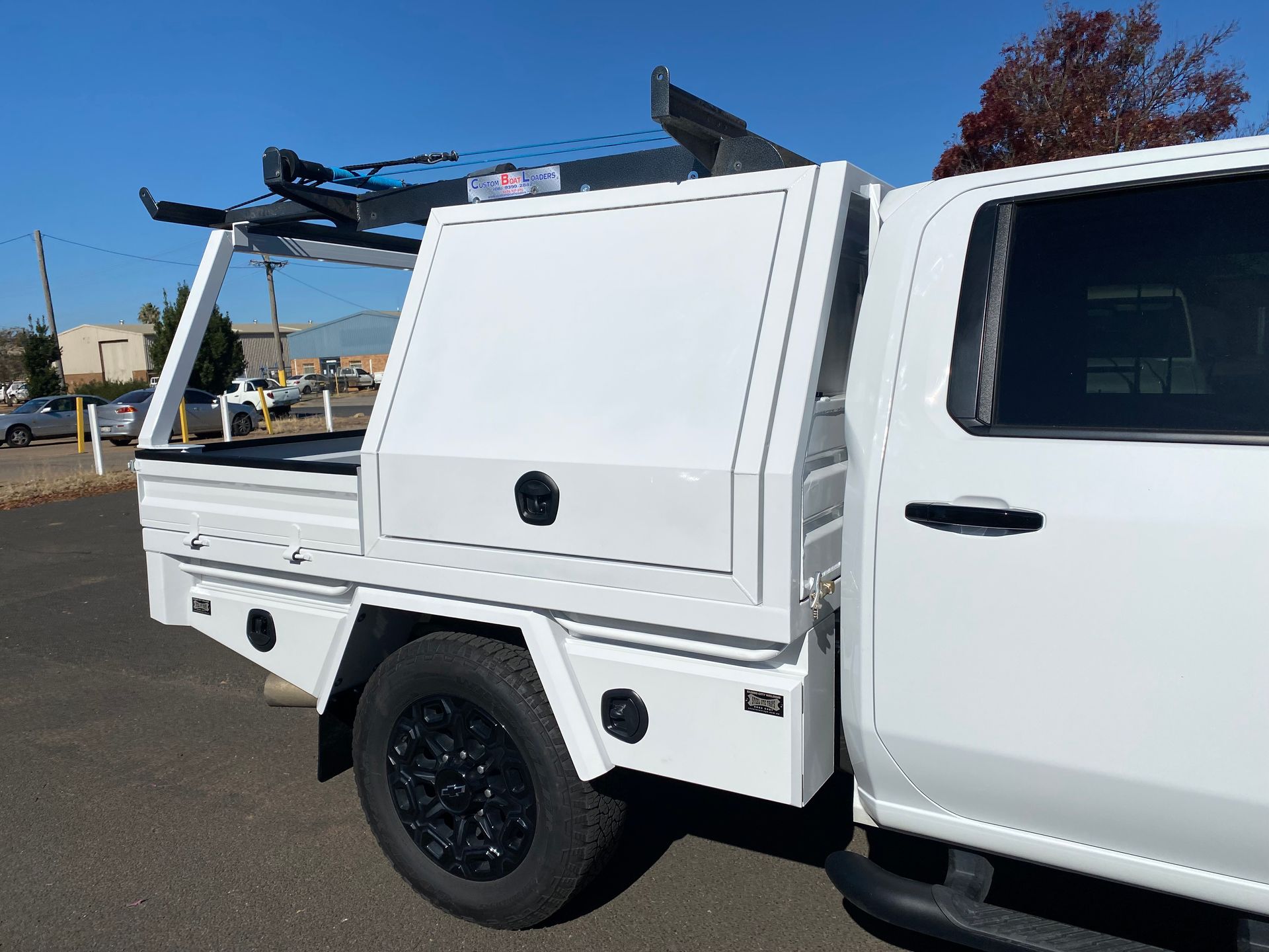 A white truck with a canopy on top of it is parked on the side of the road.