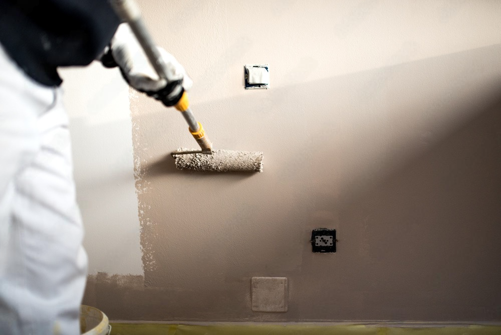 A person is painting a wall with a roller.