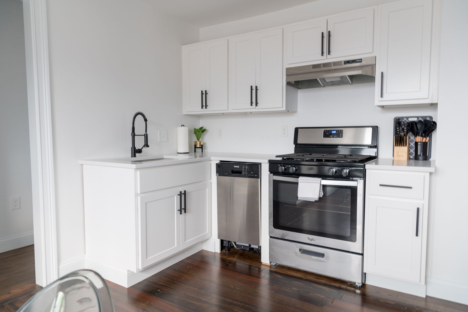 A kitchen with white cabinets , stainless steel appliances , a sink , and a stove.